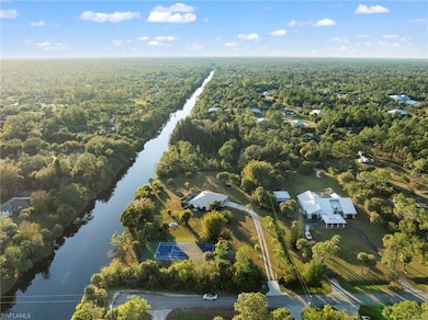 Birds eye view of property with a water view; corner lot extending beyond tall dark green trees - 5+ Acres