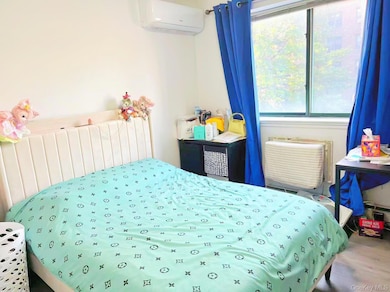 Bedroom featuring radiator heating unit, a wall unit AC, and a wall mounted AC