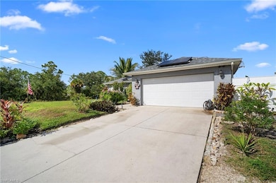 View of side of home featuring roof mounted solar panels, concrete driveway, stucco siding, and a yard