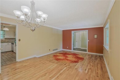 Unfurnished room with light wood finished floors, a chandelier, ornamental molding, baseboards, and a textured ceiling
