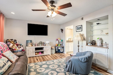 Living room with light wood-style flooring, ceiling fan, and recessed lighting