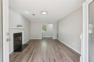 Unfurnished living room featuring a glass covered fireplace, wood finished floors, and crown molding