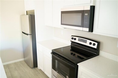 Kitchen with stainless steel appliances, white cabinetry, and light countertops
