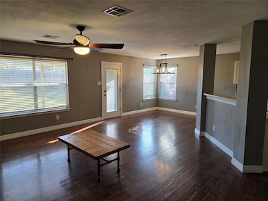 Unfurnished living room with dark wood-style flooring, a textured ceiling, and a ceiling fan