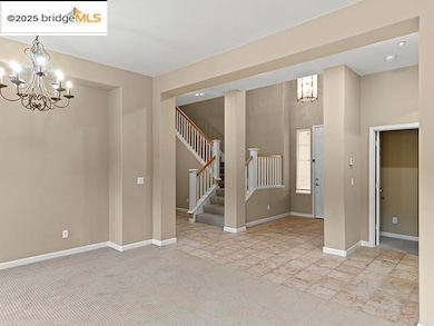 Empty room with a chandelier, stairs, and light carpet