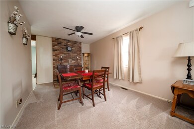 Carpeted dining area featuring brick wall and ceiling fan
