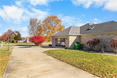 View of property exterior featuring a lawn, brick siding, a shingled roof, and driveway