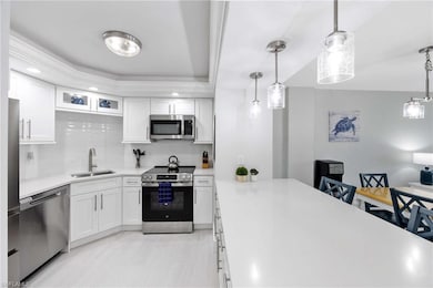 Kitchen featuring appliances with stainless steel finishes, decorative backsplash, light countertops, white cabinets, and recessed lighting