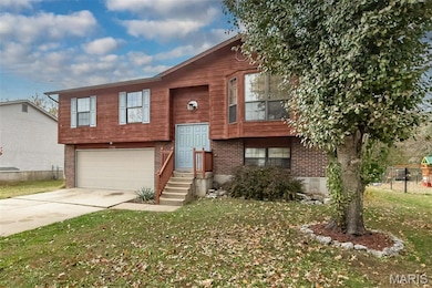 Split foyer home featuring concrete driveway, brick siding, and an attached garage