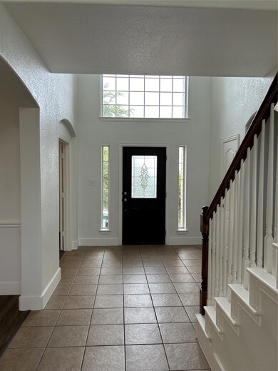 Tiled entrance foyer featuring a towering ceiling