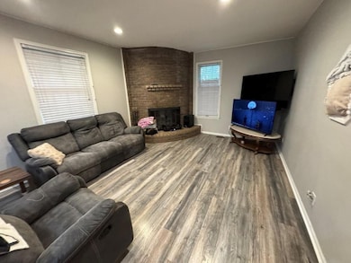 Living room featuring a brick fireplace, wood finished floors, and recessed lighting