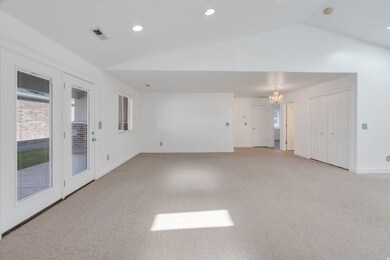 Spare room with light carpet, vaulted ceiling, a chandelier, and recessed lighting