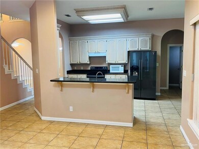 Kitchen featuring arched walkways, a kitchen breakfast bar, black appliances, a peninsula, and light tile patterned flooring