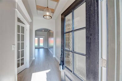 Hall with arched walkways, french doors, and wood finished floors