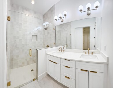 Bathroom featuring a stall shower and double vani