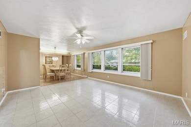 Empty room with a ceiling fan and light tile patterned floors