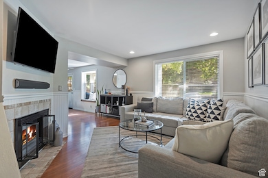 Living room with healthy amount of natural light, wood finished floors, a tile fireplace, and recessed lighting