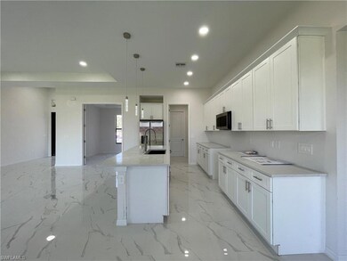 Kitchen featuring stainless steel microwave, a sink, recessed lighting, light marble finish floors, and white cabinetry