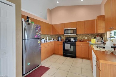 Kitchen featuring stainless steel appliances, decorative backsplash, high vaulted ceiling, light tile patterned flooring, and light countertops