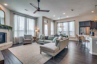 Living room featuring vinyl wood-style flooring, plenty of natural light, ceiling fan, and a stone gas fireplace