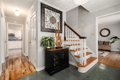 Staircase featuring ornamental molding, a textured ceiling, a chandelier, and wood finished floors