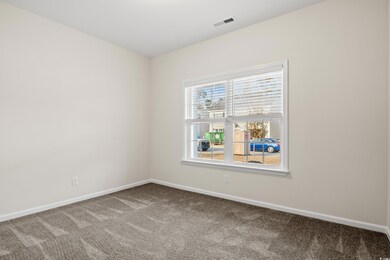 Carpeted spare room featuring visible vents and ba