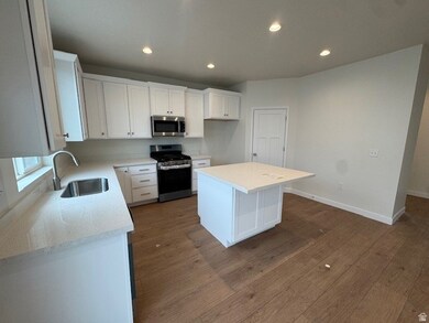 Kitchen featuring stainless steel appliances, white cabinetry, a kitchen island, recessed lighting, and dark wood finished floors