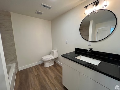 Full bathroom featuring vanity, dark wood finished floors, a tub to relax in, and a textured ceiling