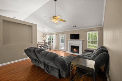 Living area with wood finished floors, ornamental molding, a ceiling fan, plenty of natural light, and lofted ceiling