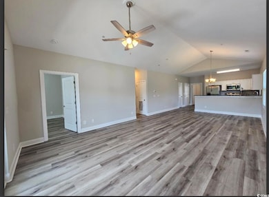 Unfurnished living room featuring baseboards, wood