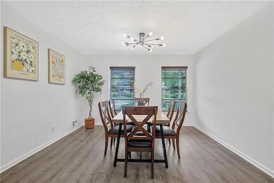 Dining space featuring a chandelier, wood finished floors, baseboards, and a textured ceiling