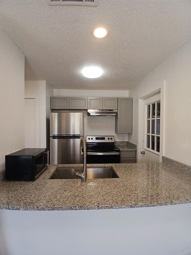 Kitchen with refrigerator, range, gray cabinetry,