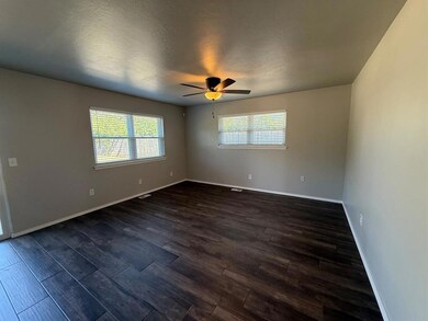 Unfurnished room featuring healthy amount of natural light, dark wood finished floors, a textured ceiling, and a ceiling fan