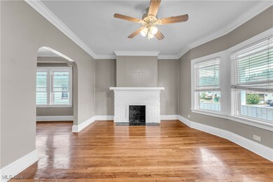 Unfurnished living room featuring crown molding, a fireplace, ceiling fan, and hardwood / wood-style flooring