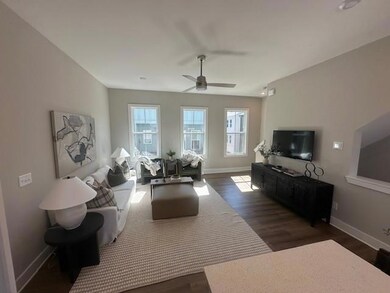 Living area featuring dark wood-type flooring and a ceiling fan