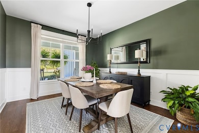 Dining room with a wainscoted wall, a decorative wall, dark wood finished floors, and a chandelier