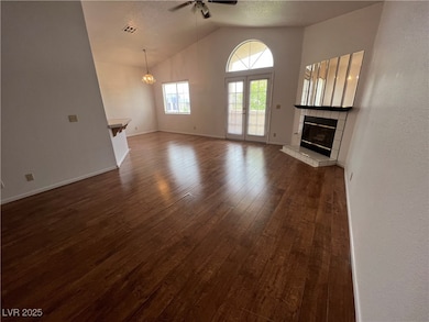 Unfurnished living room with dark wood finished floors, ceiling fan, a textured ceiling, a tile fireplace, and french doors