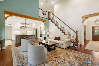 Living area with a chandelier, dark wood-style flooring, a high ceiling, stairs, and recessed lighting