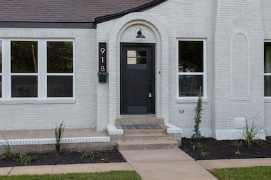 Its whitewashed brick façade, lush green lawn, and freshly mulched flower beds give it an inviting curb appeal.