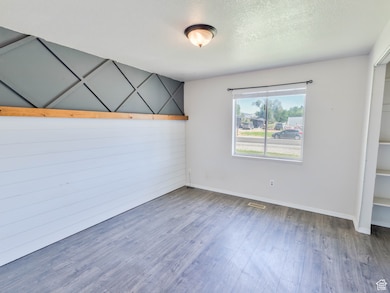 Unfurnished bedroom with wood finished floors, baseboards, and a textured ceiling