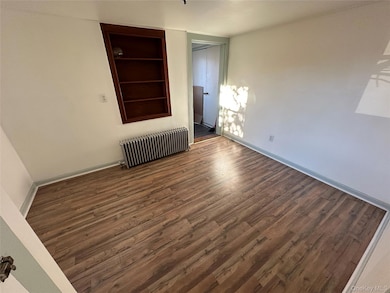 Bedroom featuring wood finished floors, built in features, and radiator