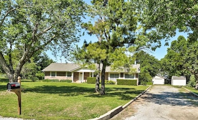 Ranch-style house featuring a front lawn, an outdoor structure, driveway, and brick siding