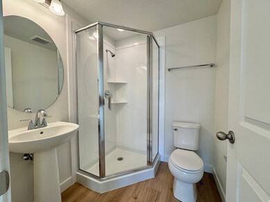 Bathroom featuring wood finished floors, a stall shower, and a textured ceiling