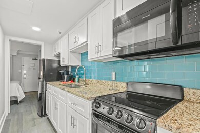 Kitchen featuring tasteful backsplash, light wood-style flooring, stainless steel appliances, white cabinets, and a sink