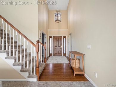 Foyer featuring a high ceiling, dark wood-style floors, and a chandelier