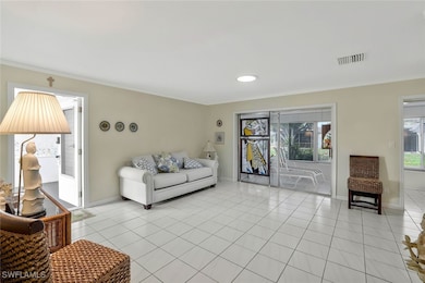 Living room featuring light tile patterned flooring and crown molding