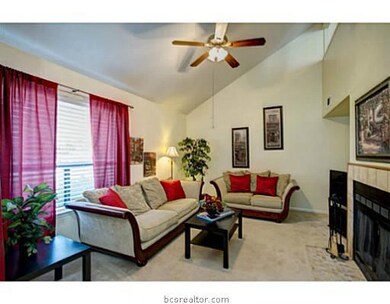 Living Room. Creating a warm environment, this carpeted living room exhibits an oversized window and a fireplace with tile detailing.