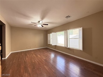 Empty room featuring a ceiling fan, dark wood-type