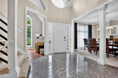 Foyer with stairs, a chandelier, granite tiled floors, a towering ceiling, and decorative columns