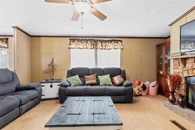 Carpeted living area featuring ornamental molding, ceiling fan, a fireplace, and a textured ceiling